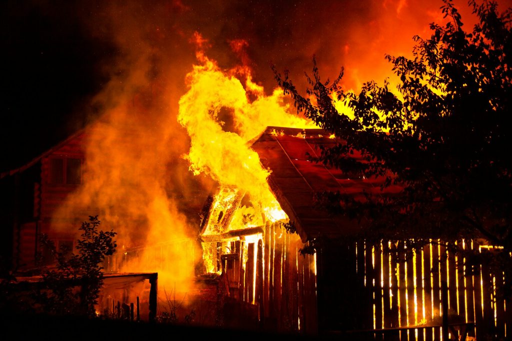 Wooden house or barn burning on fire at night