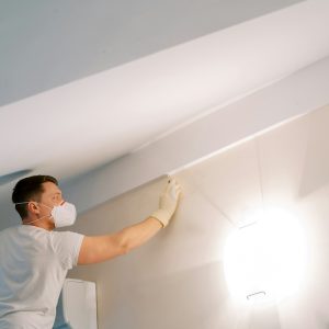 Man in a mask and gloves washes a fungus wall with a sponge